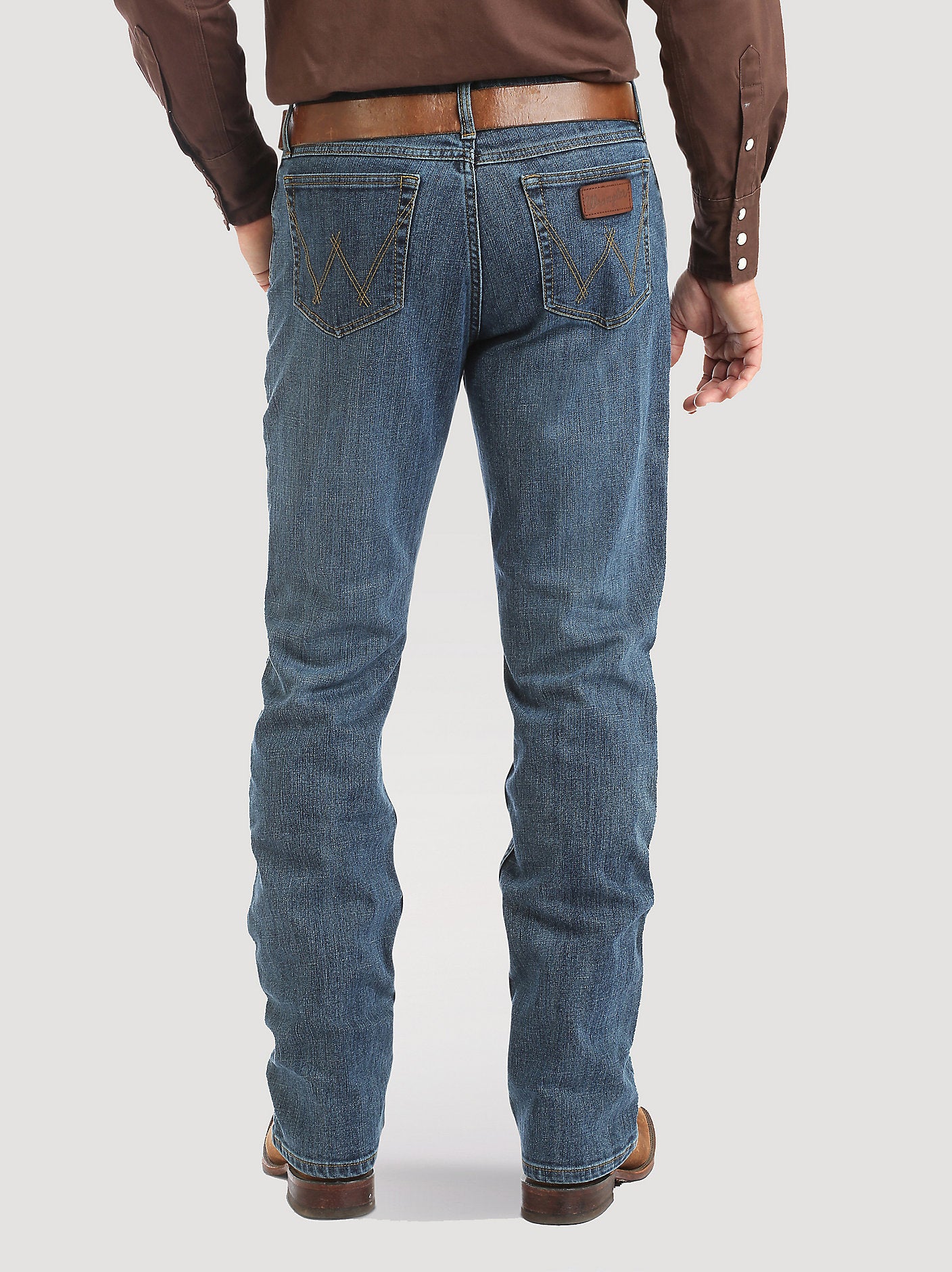 Person wearing blue jeans and a brown shirt on a white background