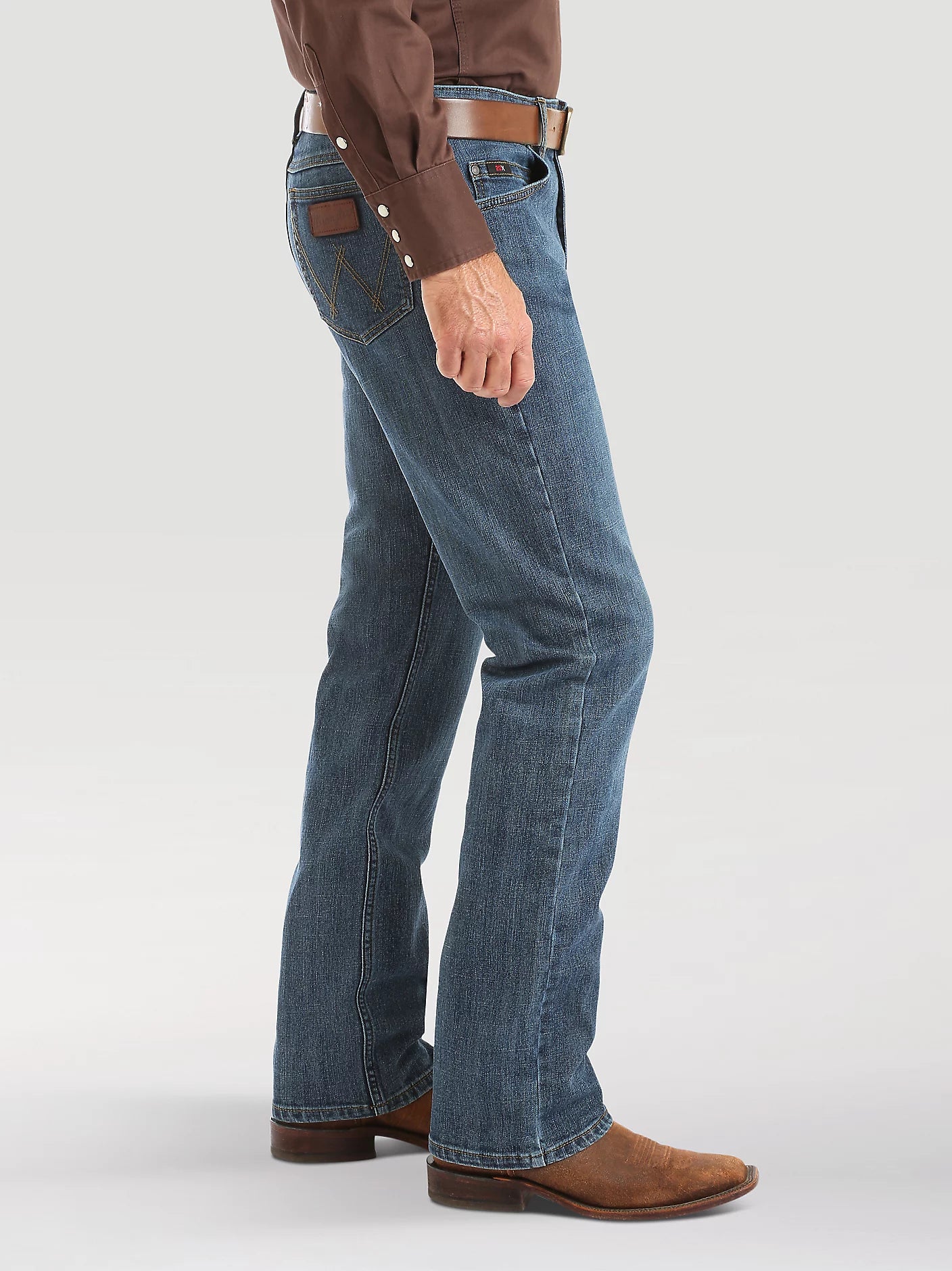 Person wearing blue jeans and brown shoes on a white background
