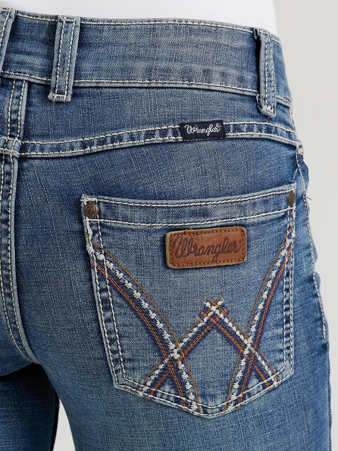 Close-up of blue denim jeans with a brand label on a white background