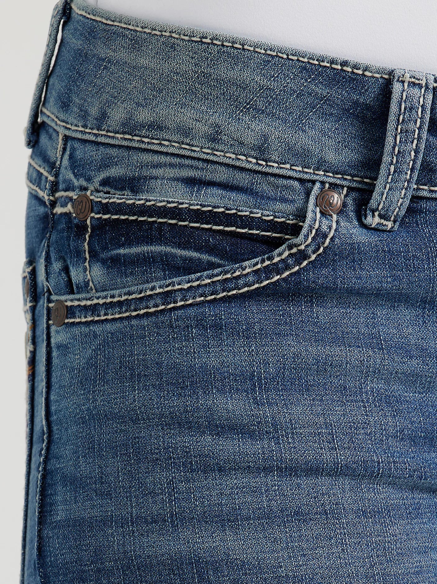 Close-up of blue jeans with stitching details on a light gray background
