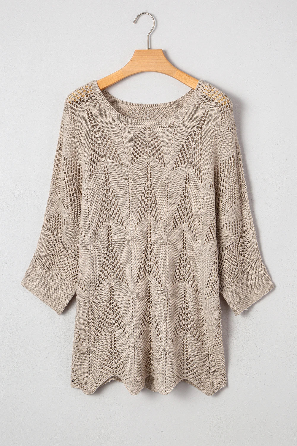 Beige knitted sweater on a wooden hanger against a white background
