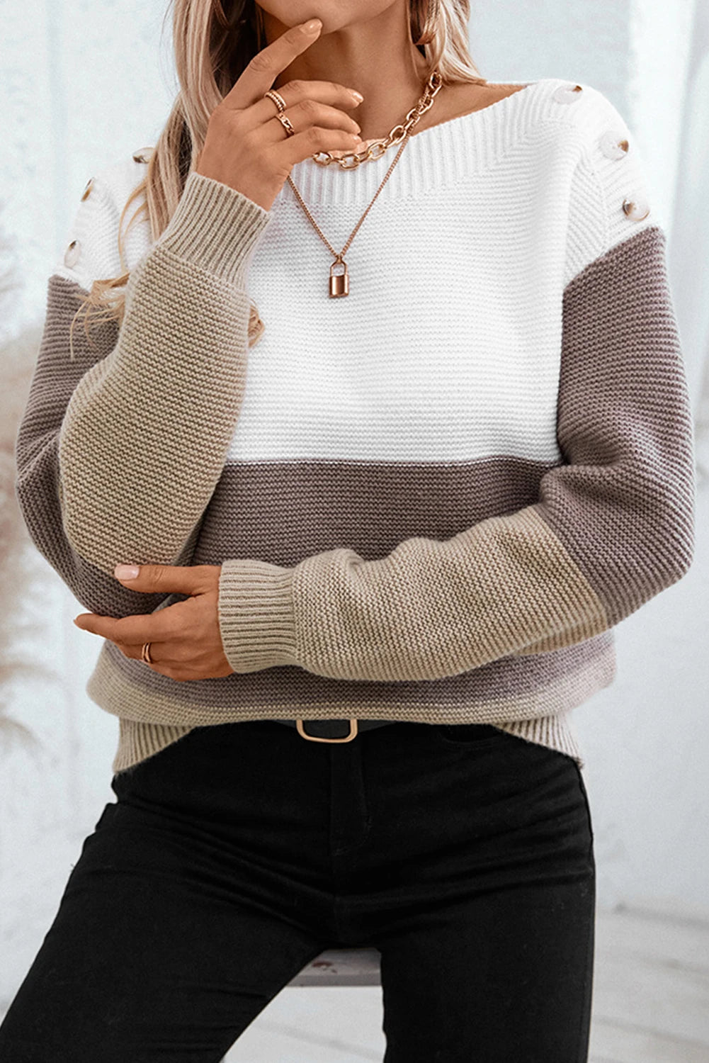 Person wearing a two-tone sweater with a white and beige design, standing against a light background.
