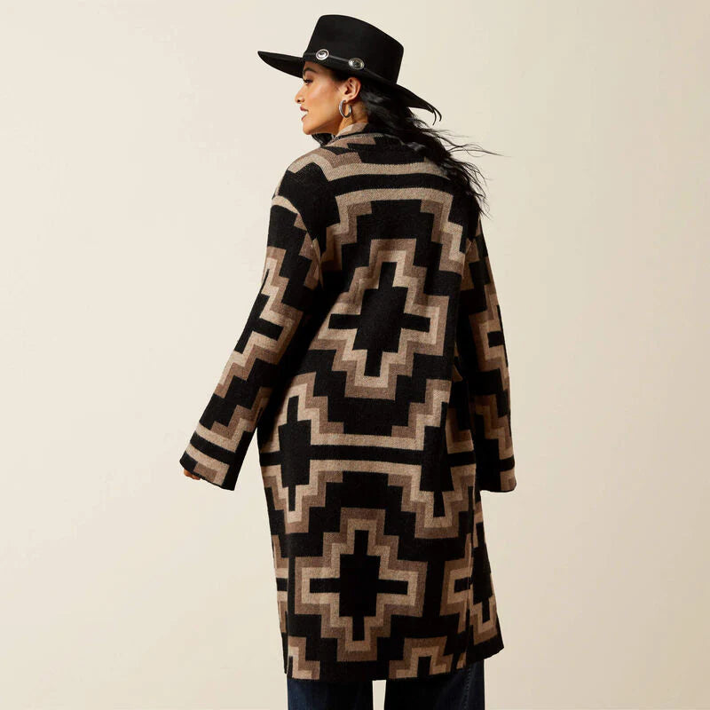 Person wearing a patterned coat and black hat on a beige background