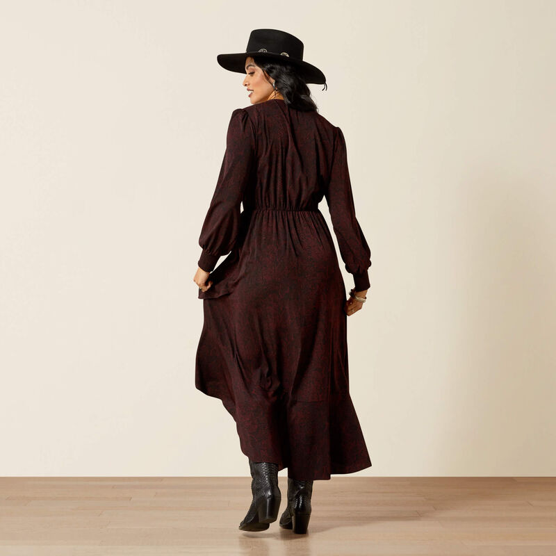Woman wearing a long brown dress and black hat on a beige background