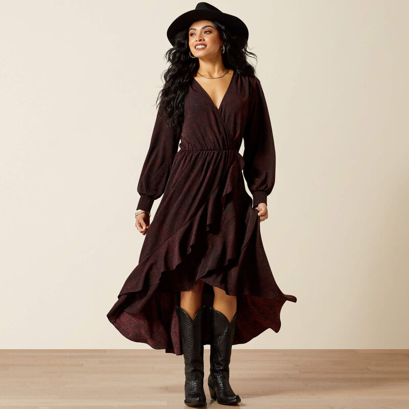 Woman wearing a long brown dress and black boots against a beige background