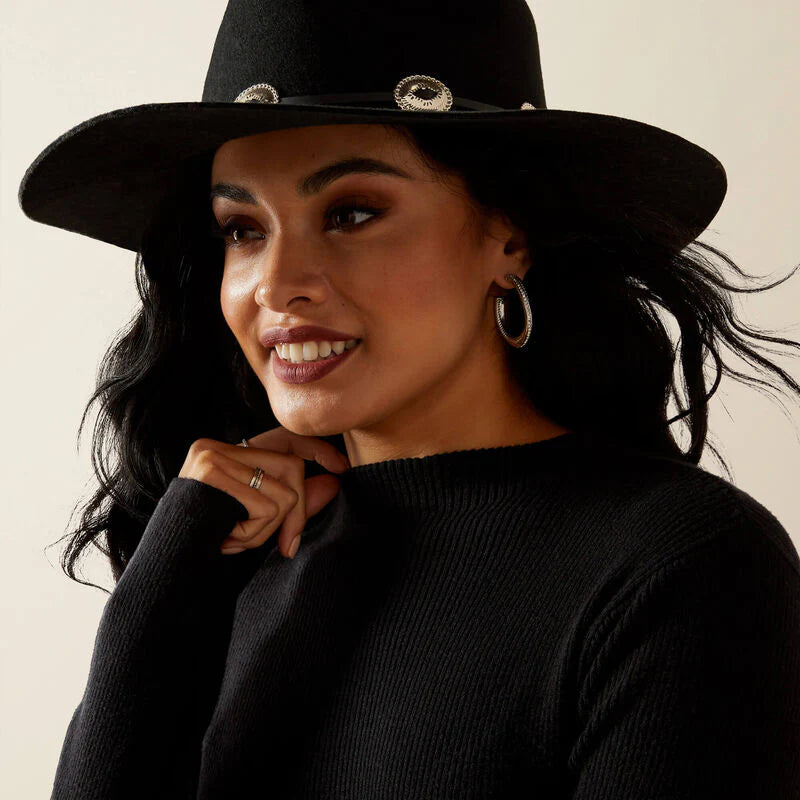 Woman wearing a black hat with decorative elements on a neutral background