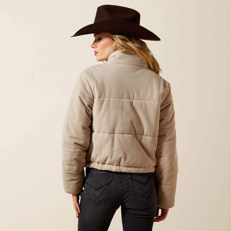 Person wearing a beige puffer jacket and brown hat on a plain background
