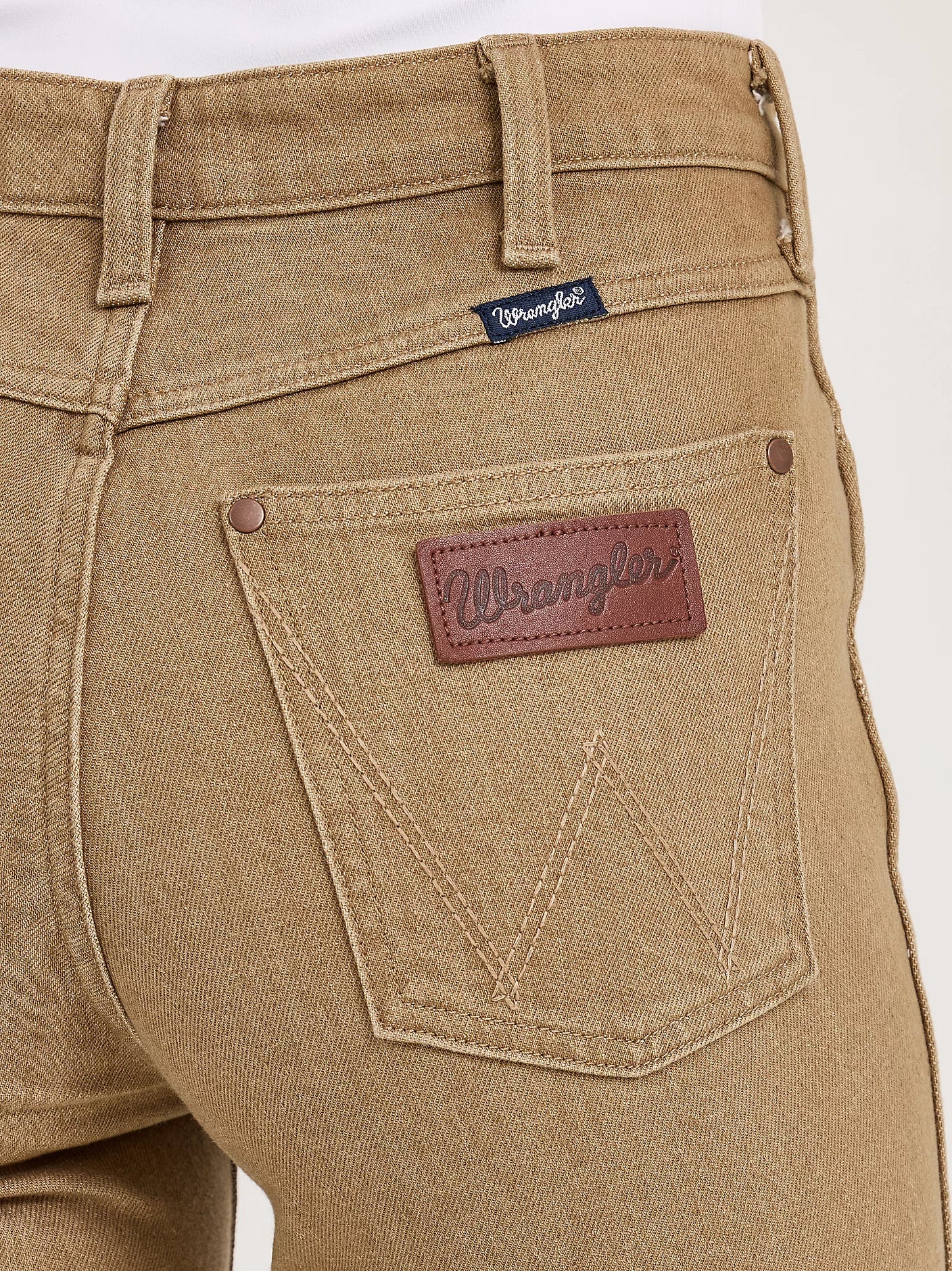 Close-up of beige Wrangler jeans with a focus on the back pocket and brand logo.