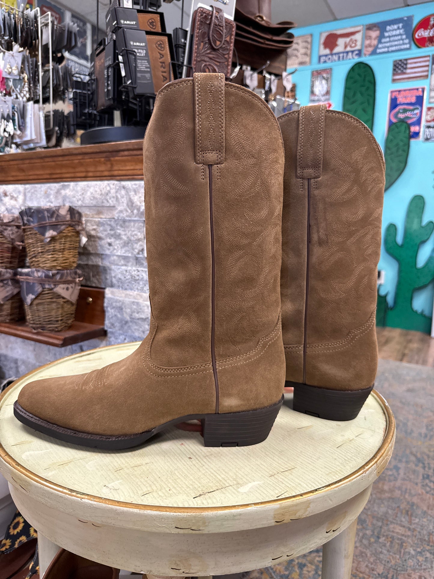 Brown suede boots on a white stool with a store interior background
