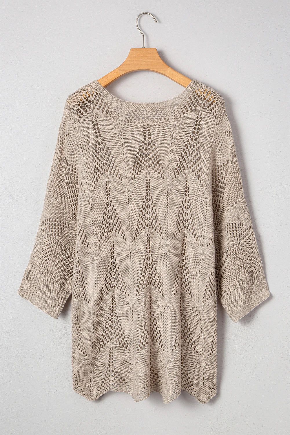 Beige knitted sweater on a wooden hanger against a white background