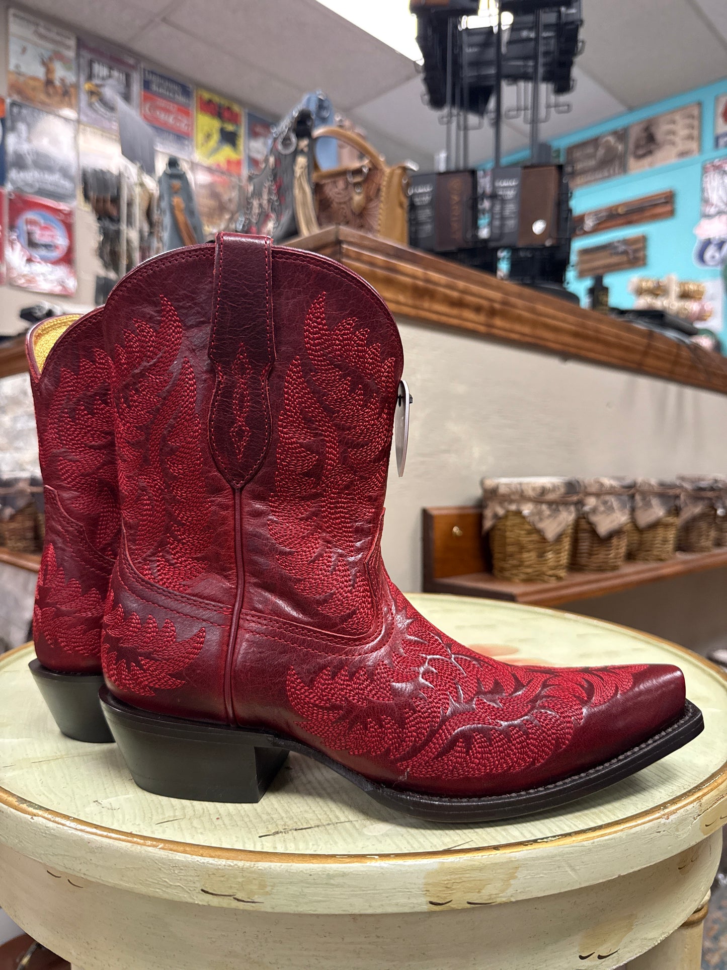 Red cowboy boot on a wooden block with a store interior in the background