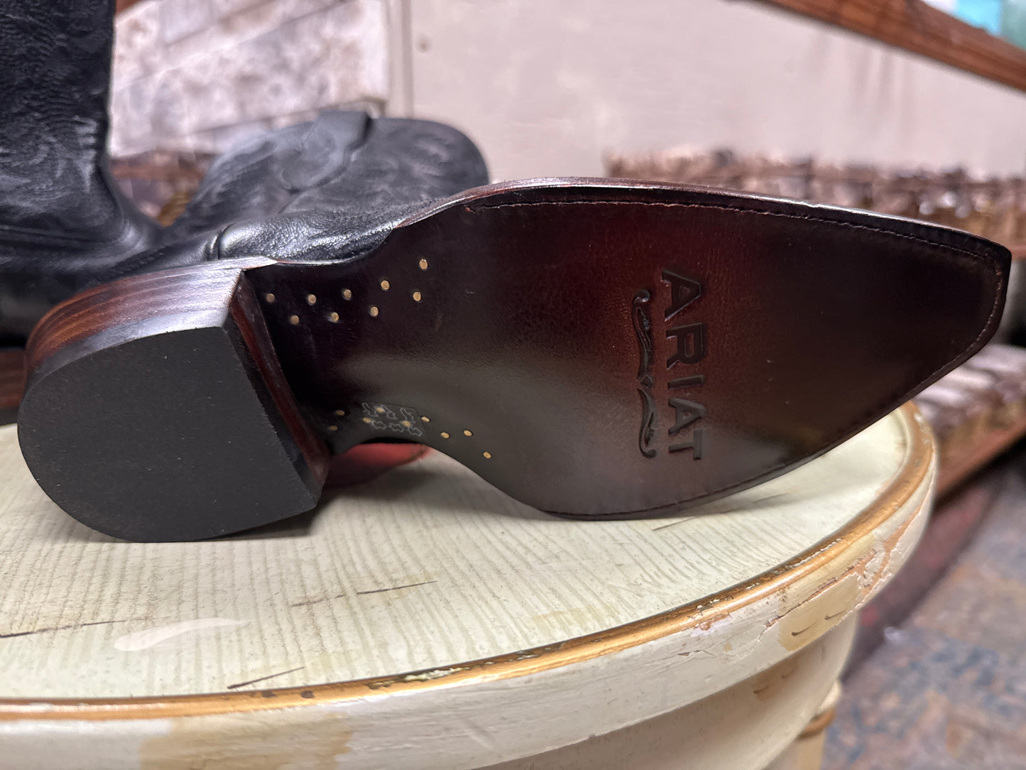 Close-up of a cowboy boot sole with 'Ariat' branding on a textured surface.
