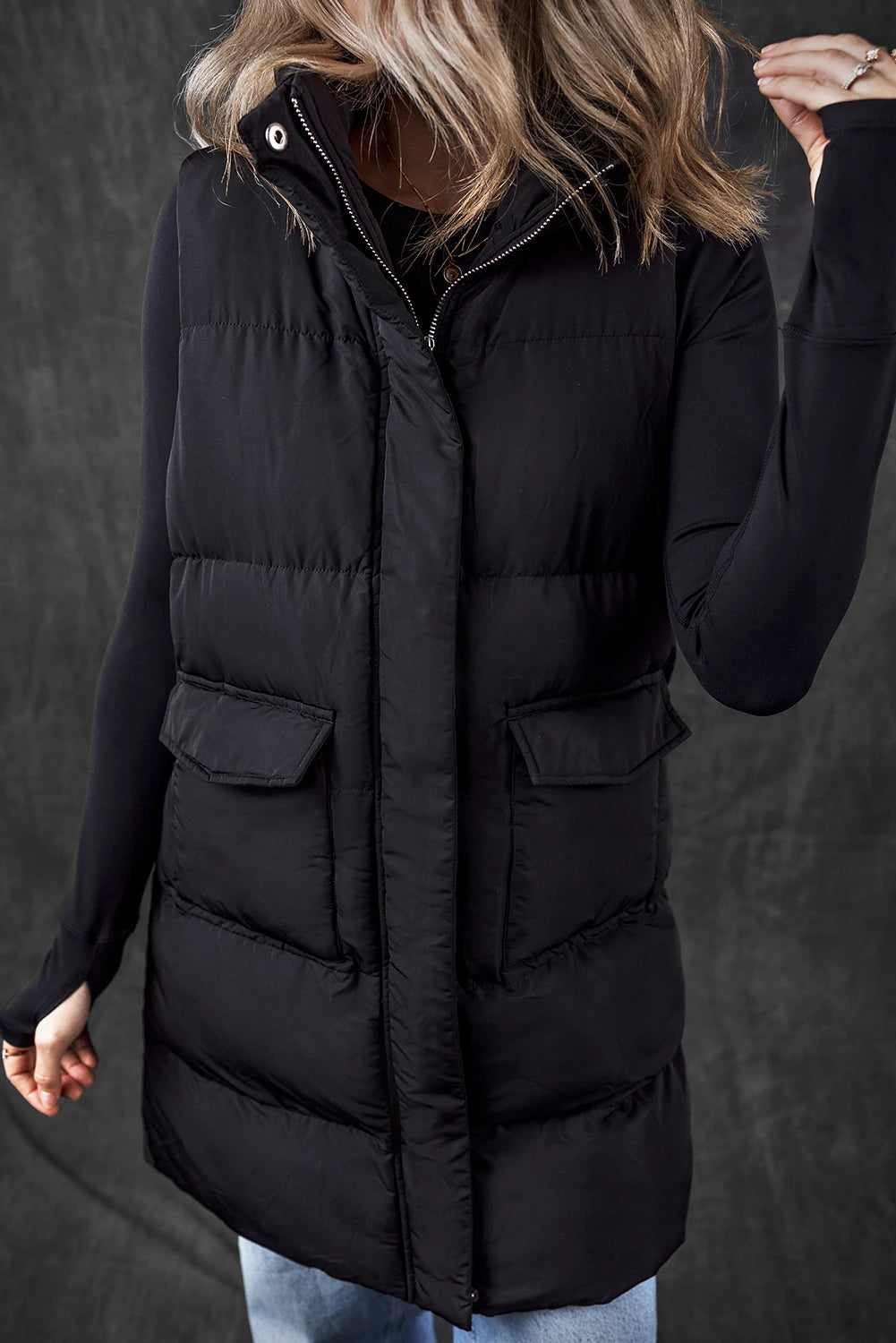 Person wearing a black puffer vest against a dark background
