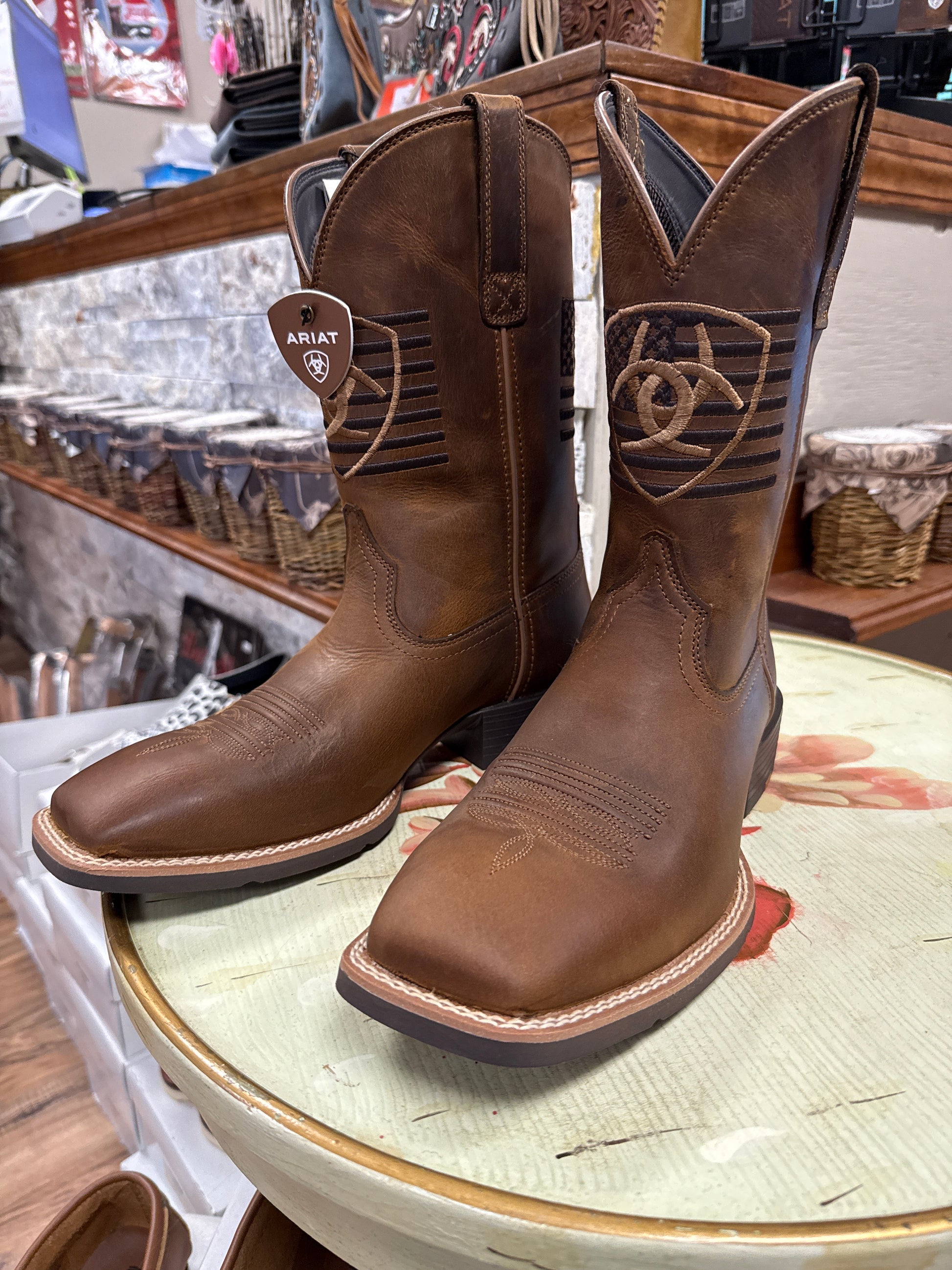 Brown leather boots with Ariat logo on a round surface