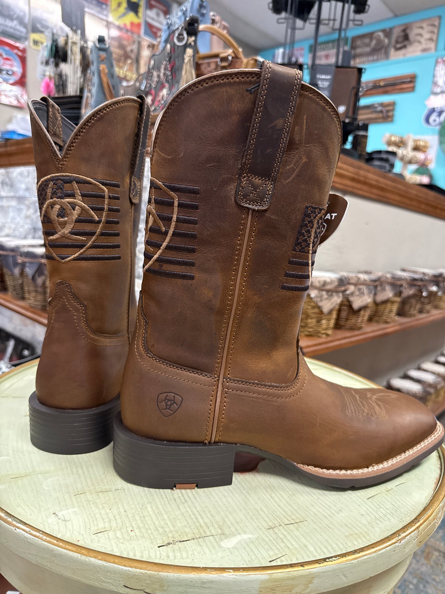 Pair of brown leather boots on a round surface with a blurred store background