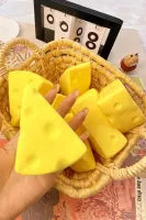 Yellow triangular sponges held by a hand with a woven basket in the background