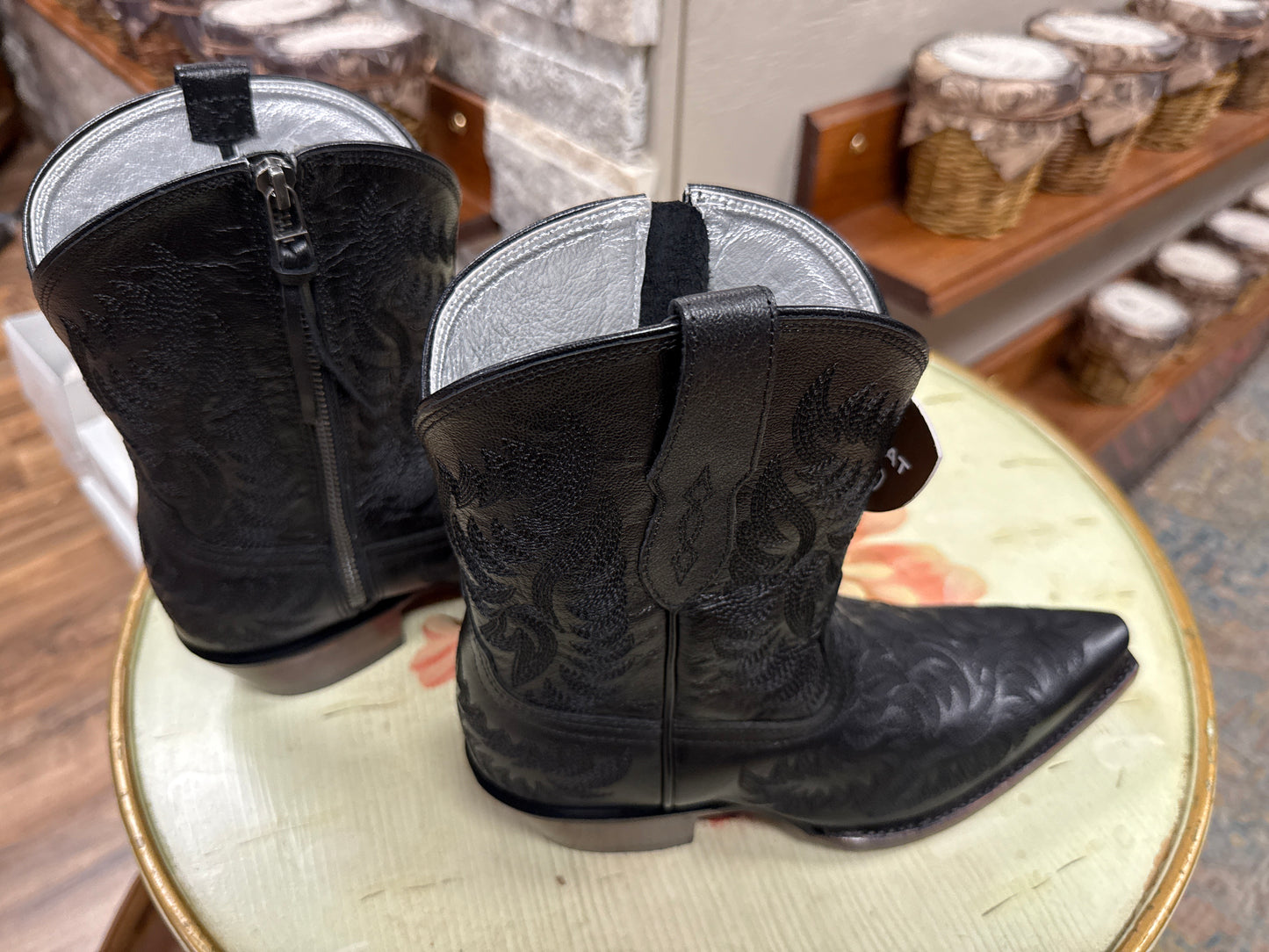 Black cowboy boots on a round white surface with a blurred background
