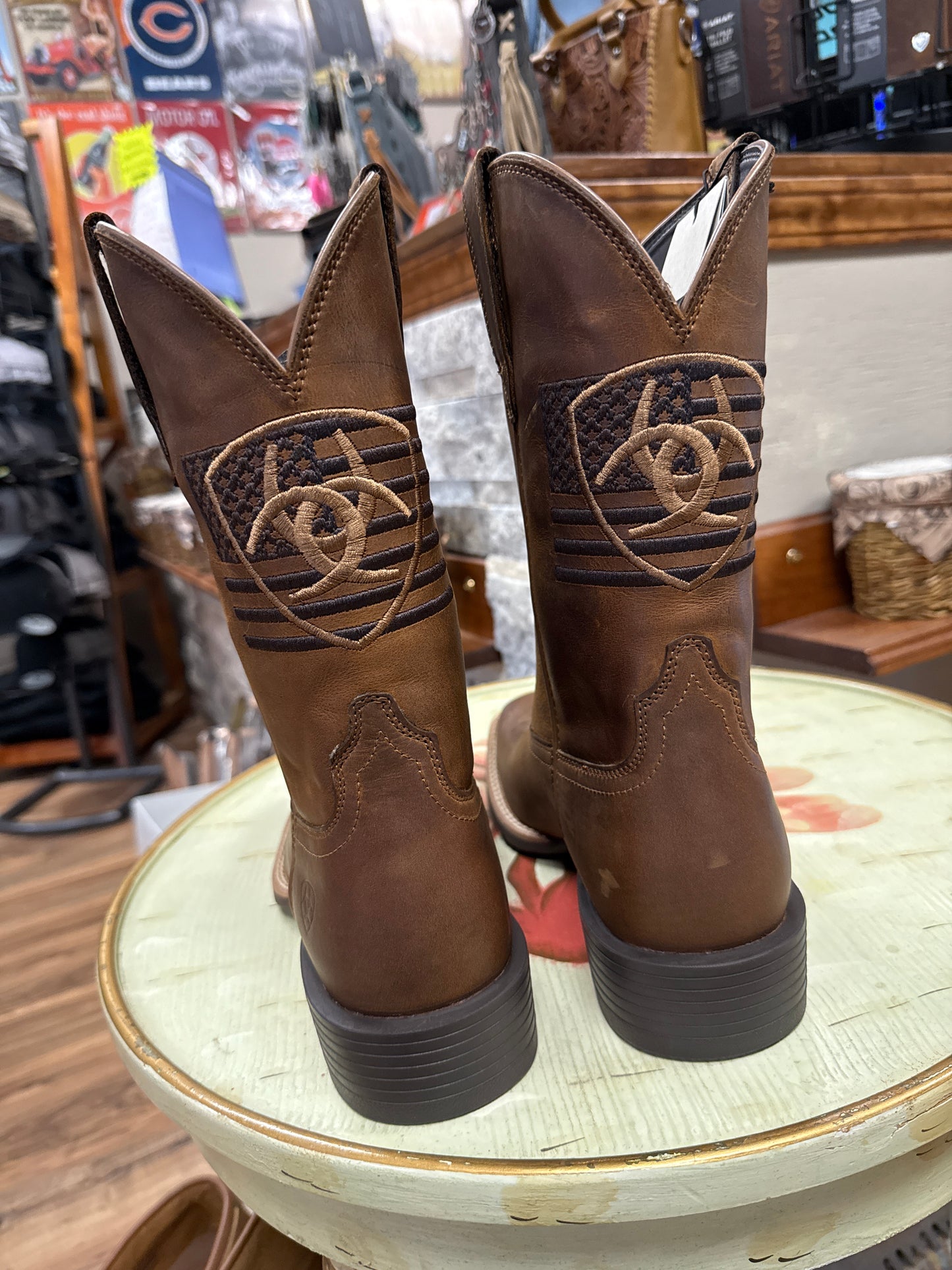 Brown boots with decorative patterns on a round wooden table.