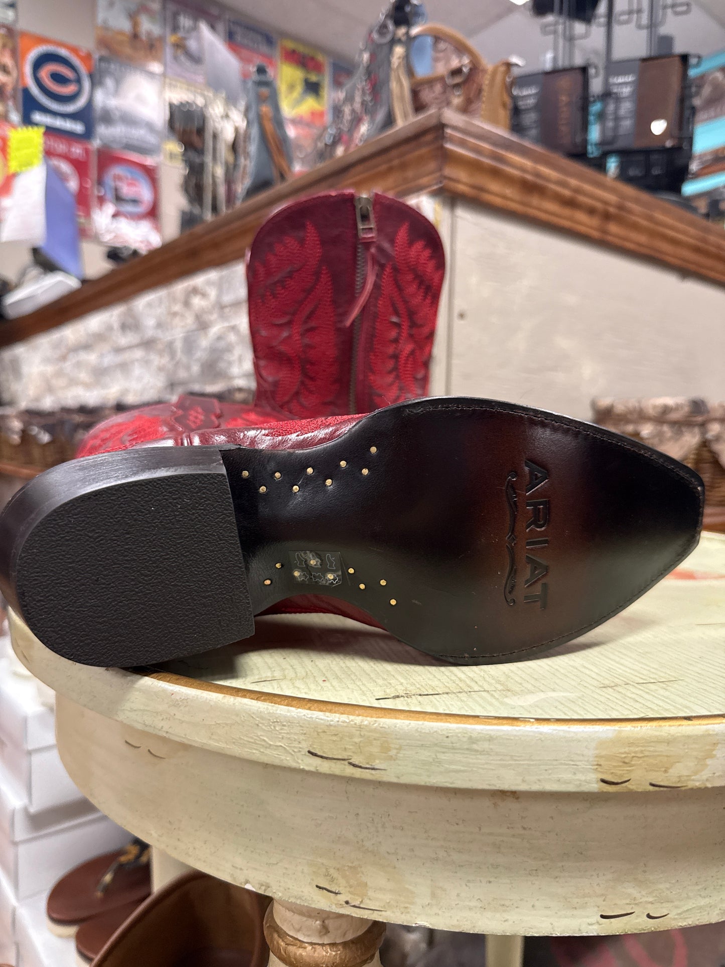Close-up of Ariat cowboy boot on a wooden barrel with store interior in the background