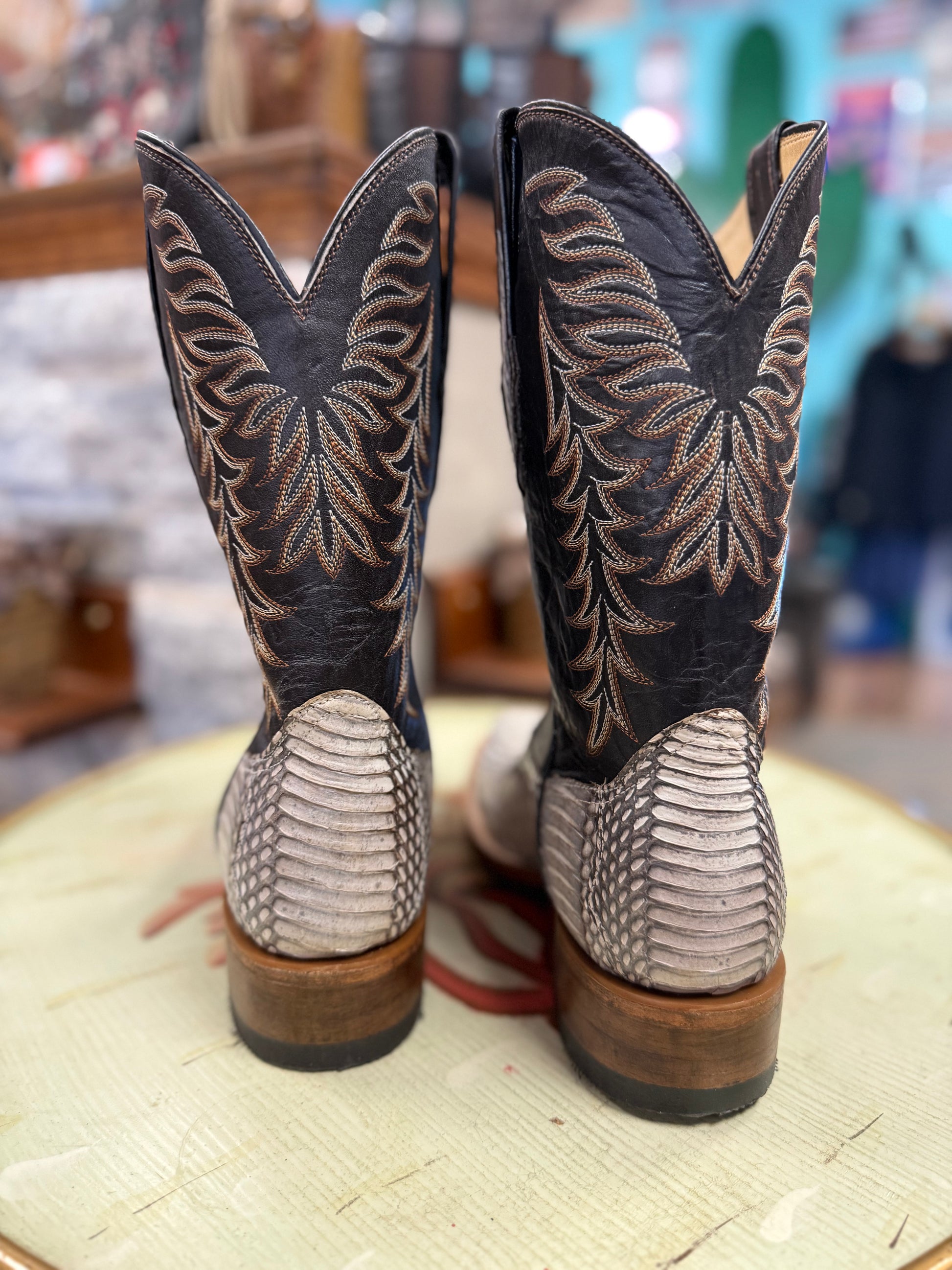 Pair of cowboy boots with intricate designs on a textured surface.