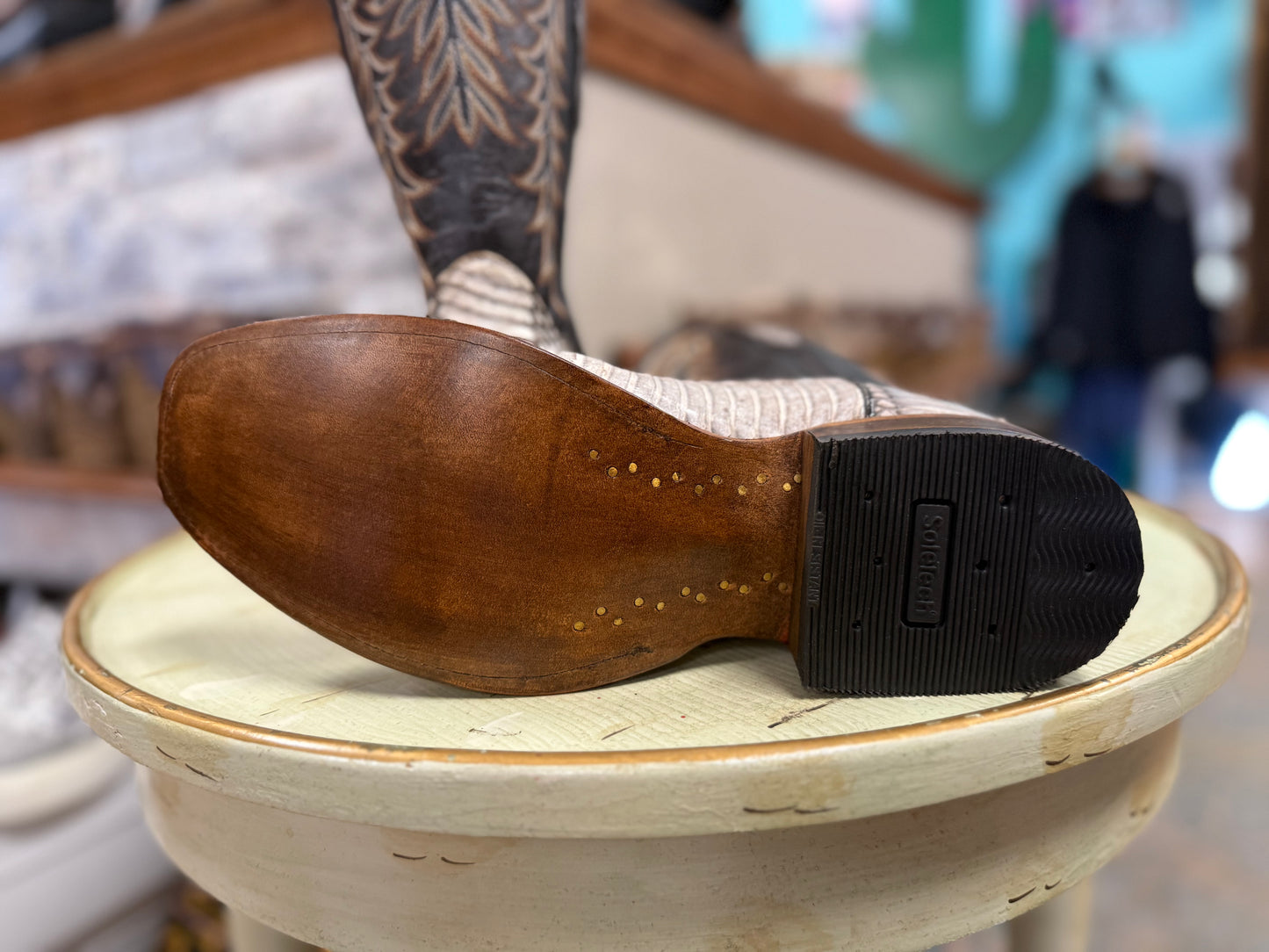 Close-up of a brown leather shoe sole on a wooden stool with a blurred background