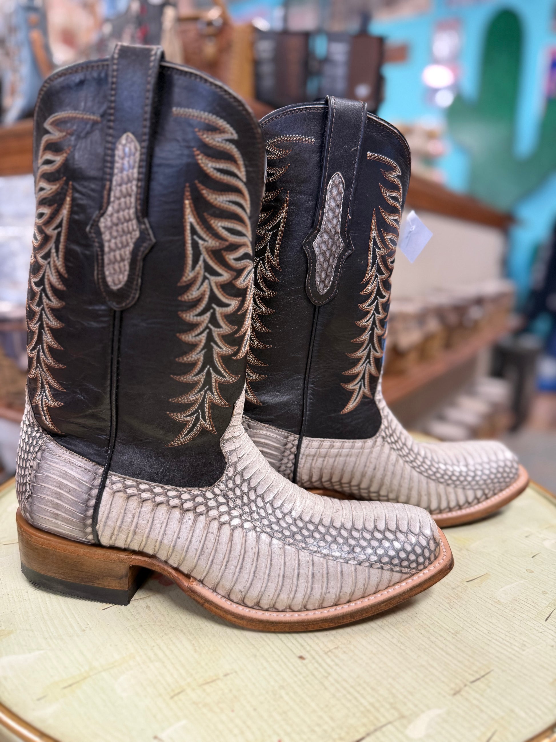 Pair of cowboy boots with intricate designs on a store floor.