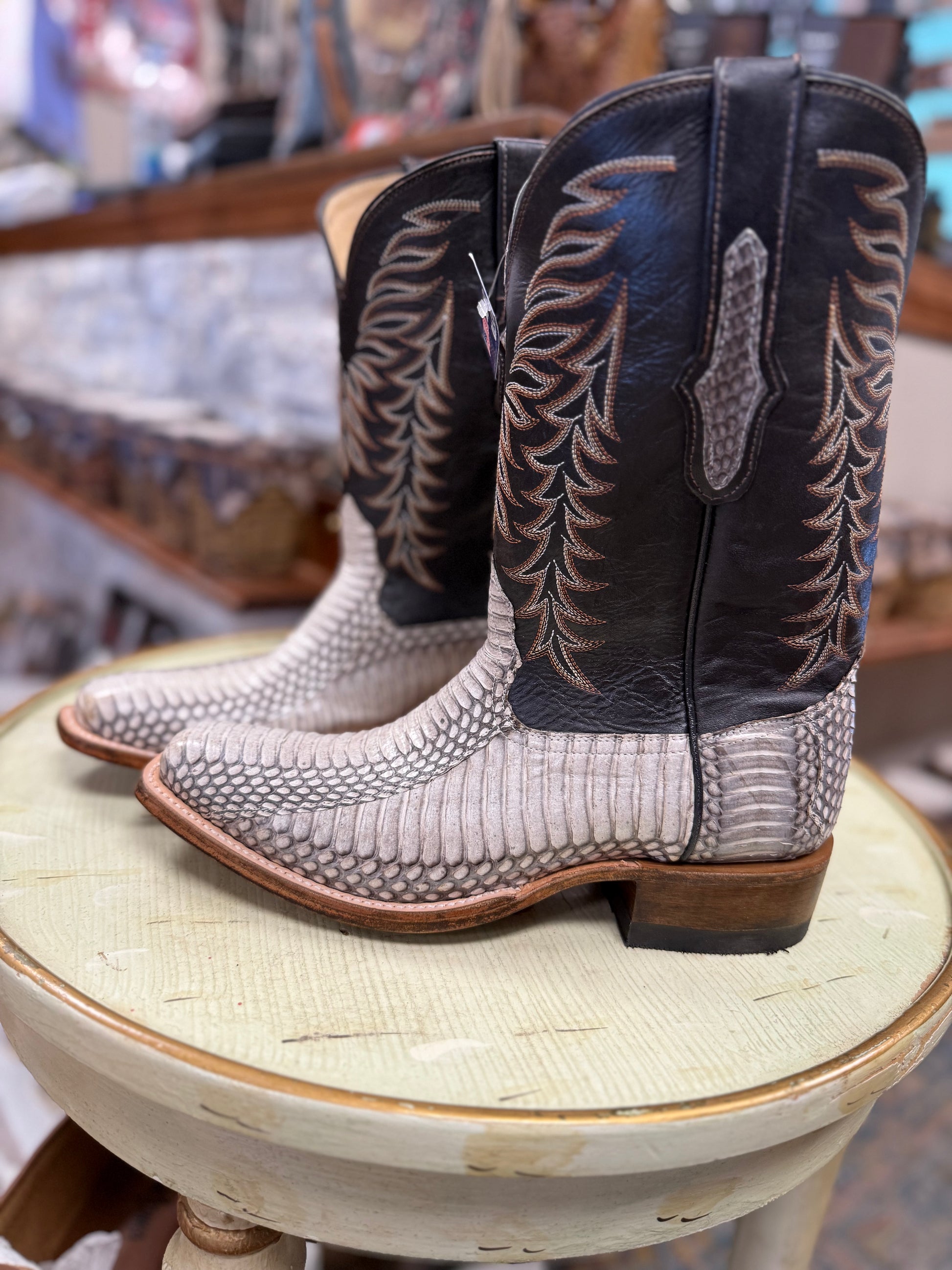 Pair of cowboy boots with intricate designs on a round stool.