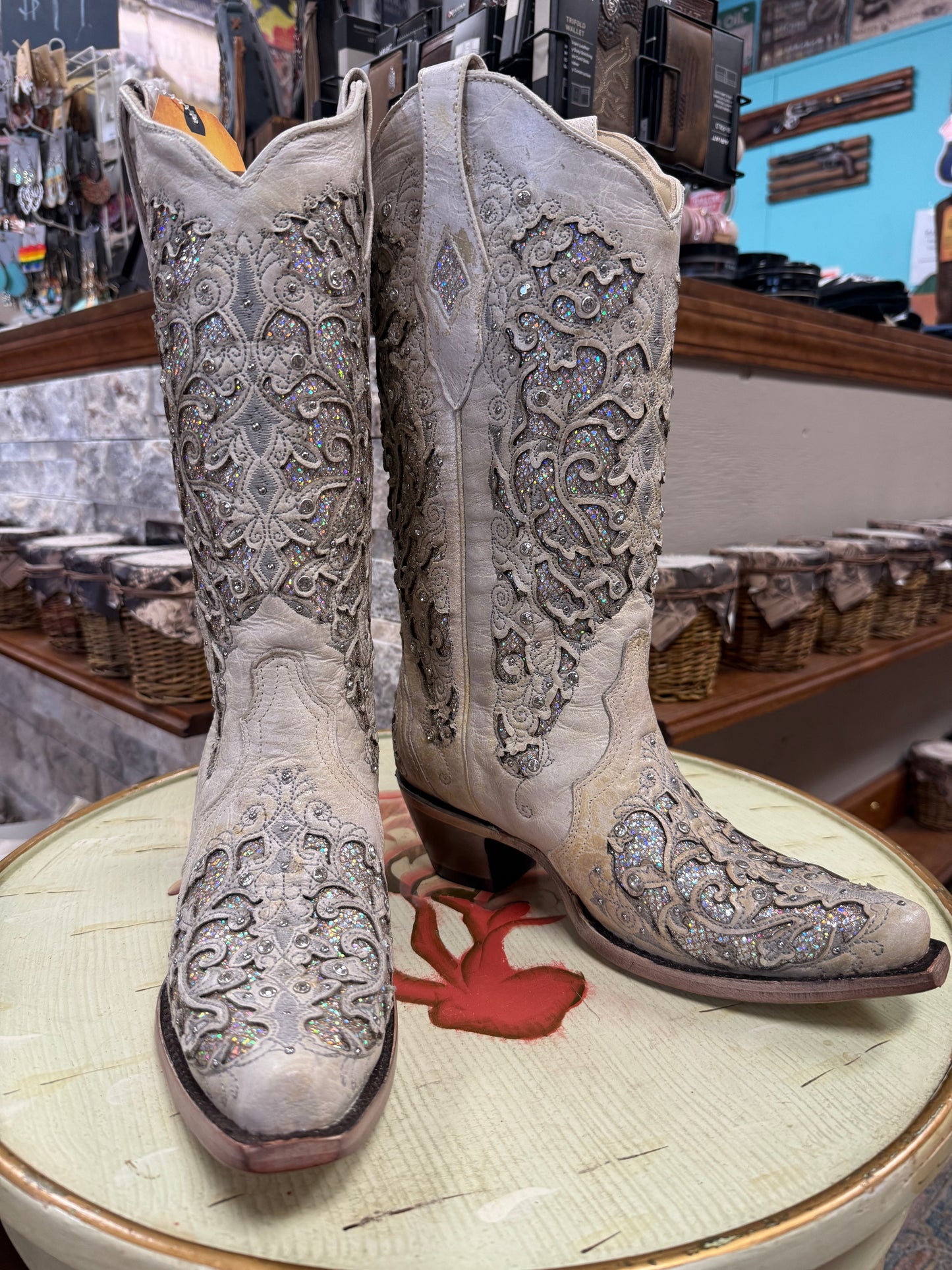 Pair of ornate cowboy boots on a round surface with a store interior in the background