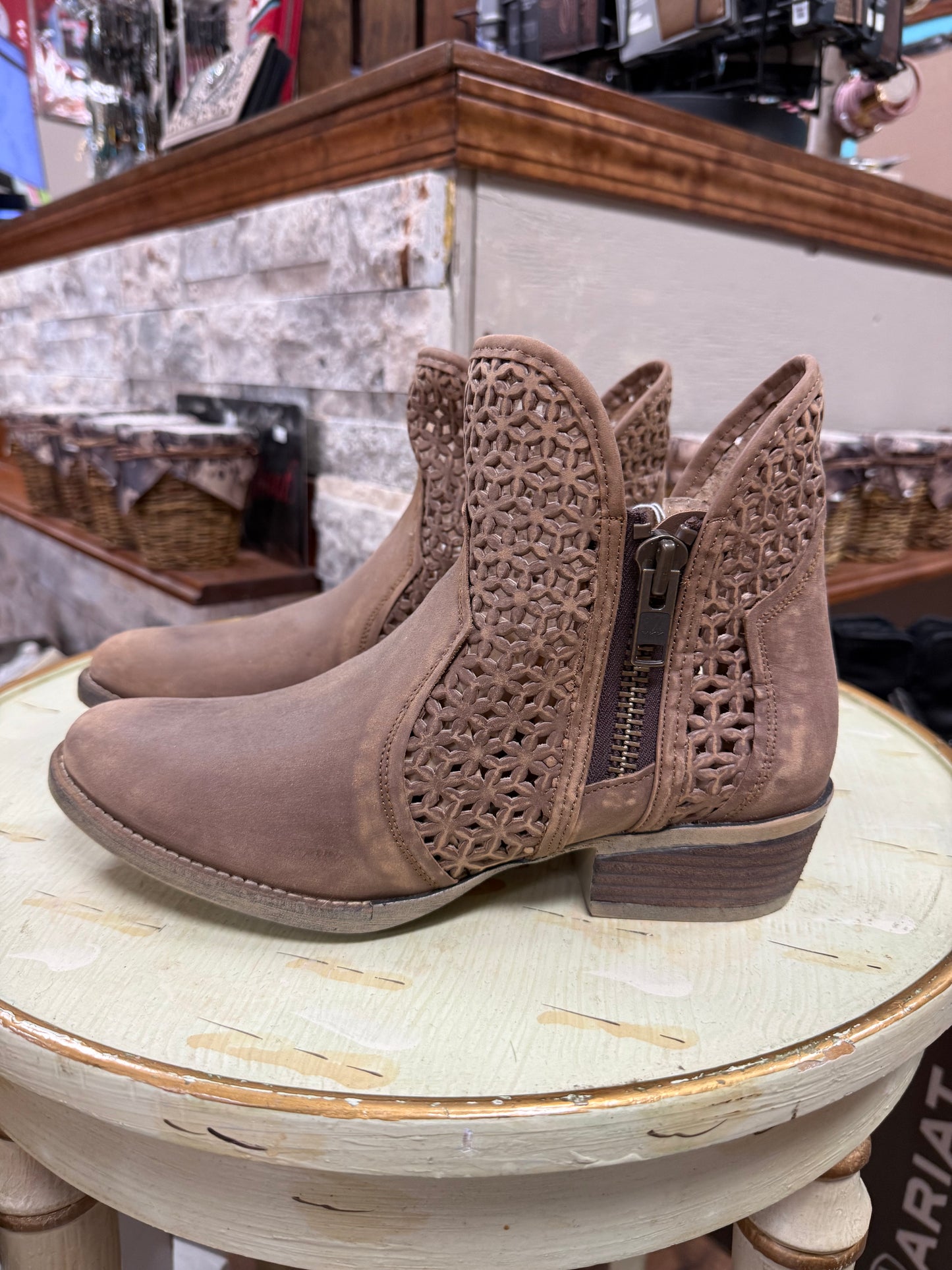 Brown ankle boots with intricate cut-out design on a round table.