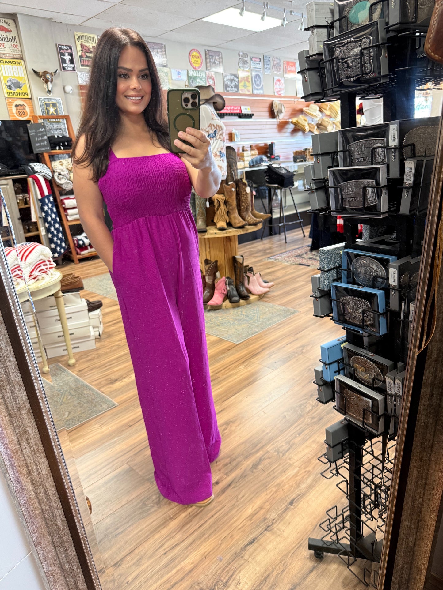 Woman in a purple dress taking a mirror selfie in a store with boots and decor on display.