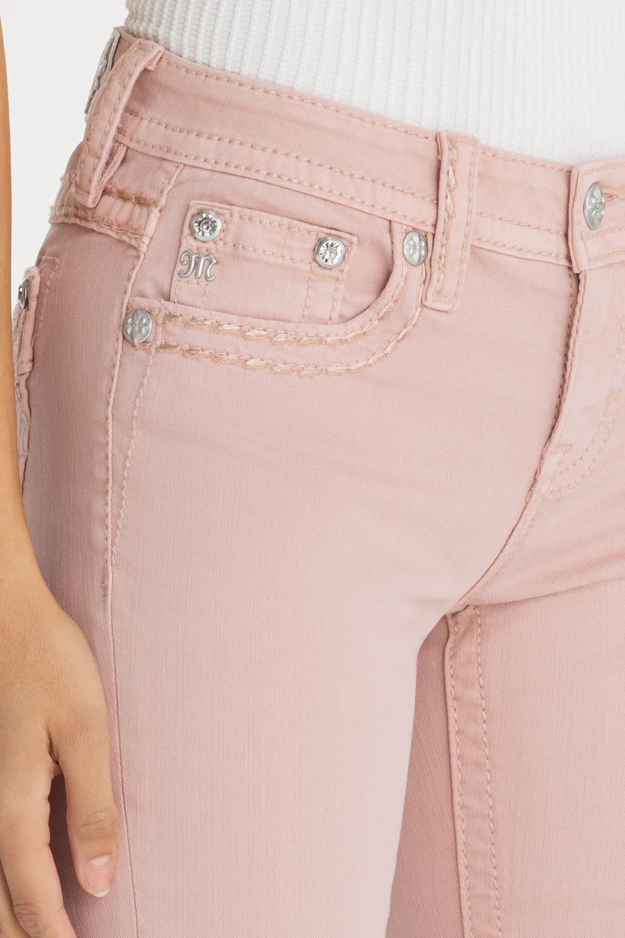 Close-up of pink jeans with decorative buttons on a light background