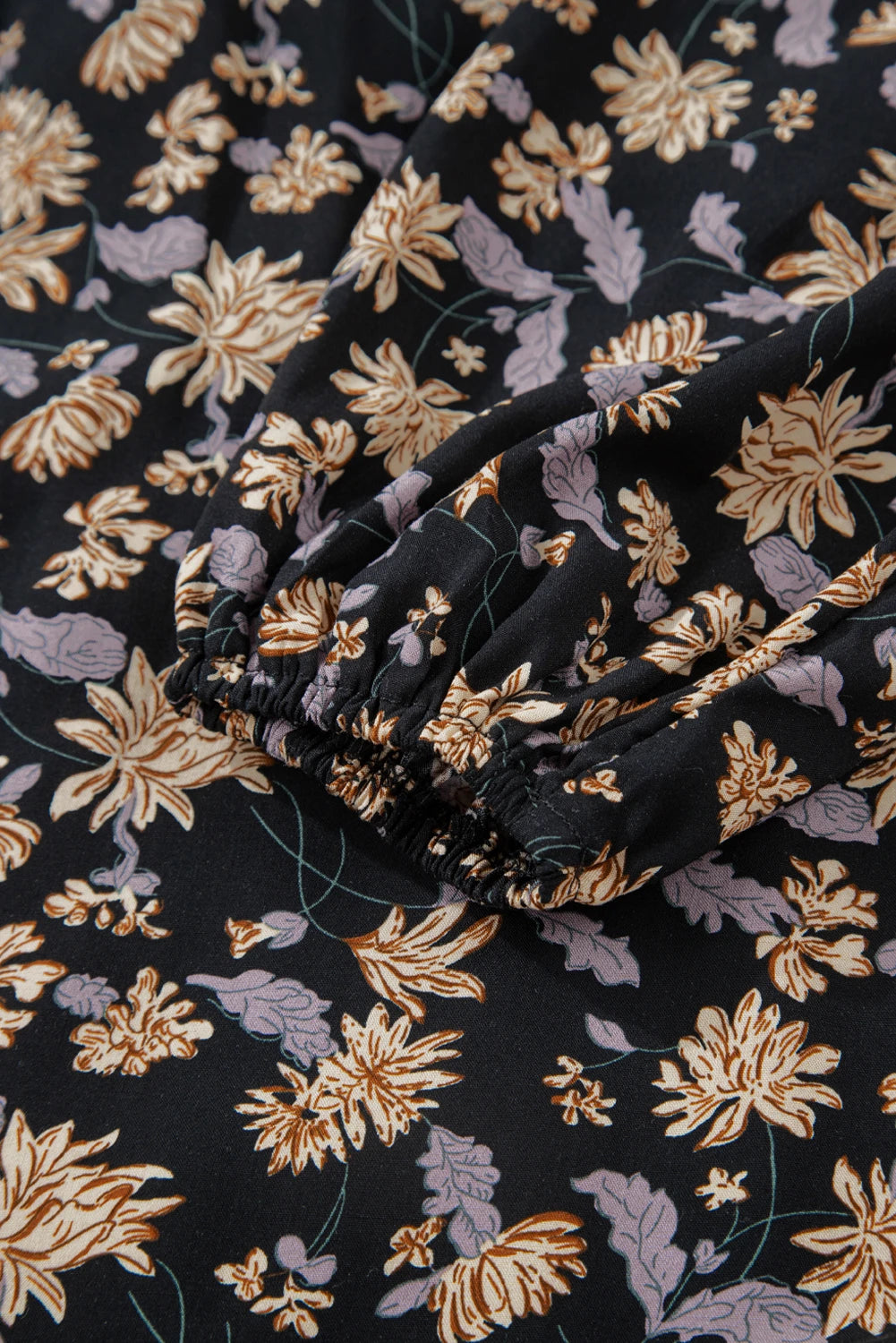 Close-up of floral-patterned fabric with gold and purple flowers on a black background