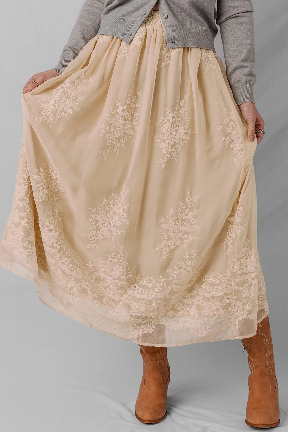 Beige lace skirt worn by a person on a gray background