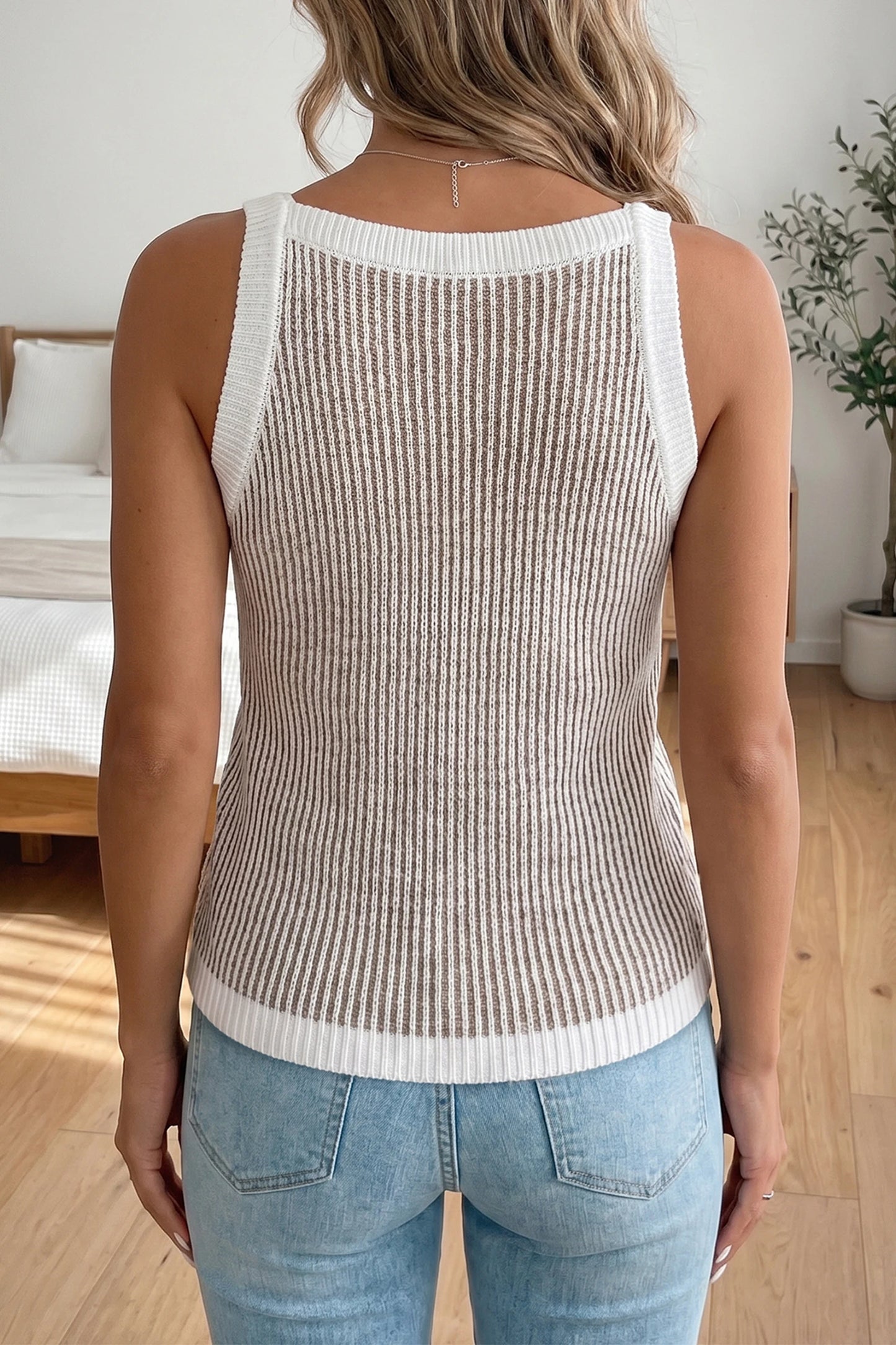 Woman wearing a ribbed knit tank top and jeans in a bedroom setting