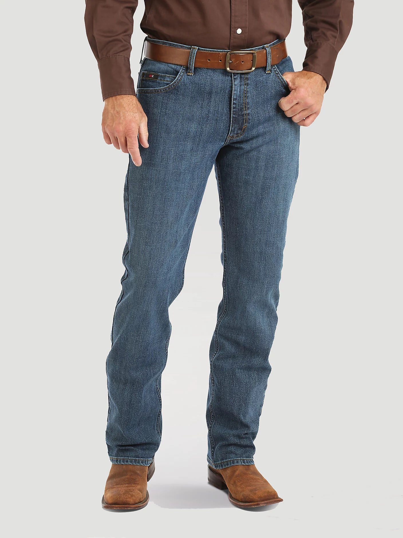 Person wearing blue jeans and brown shoes on a white background