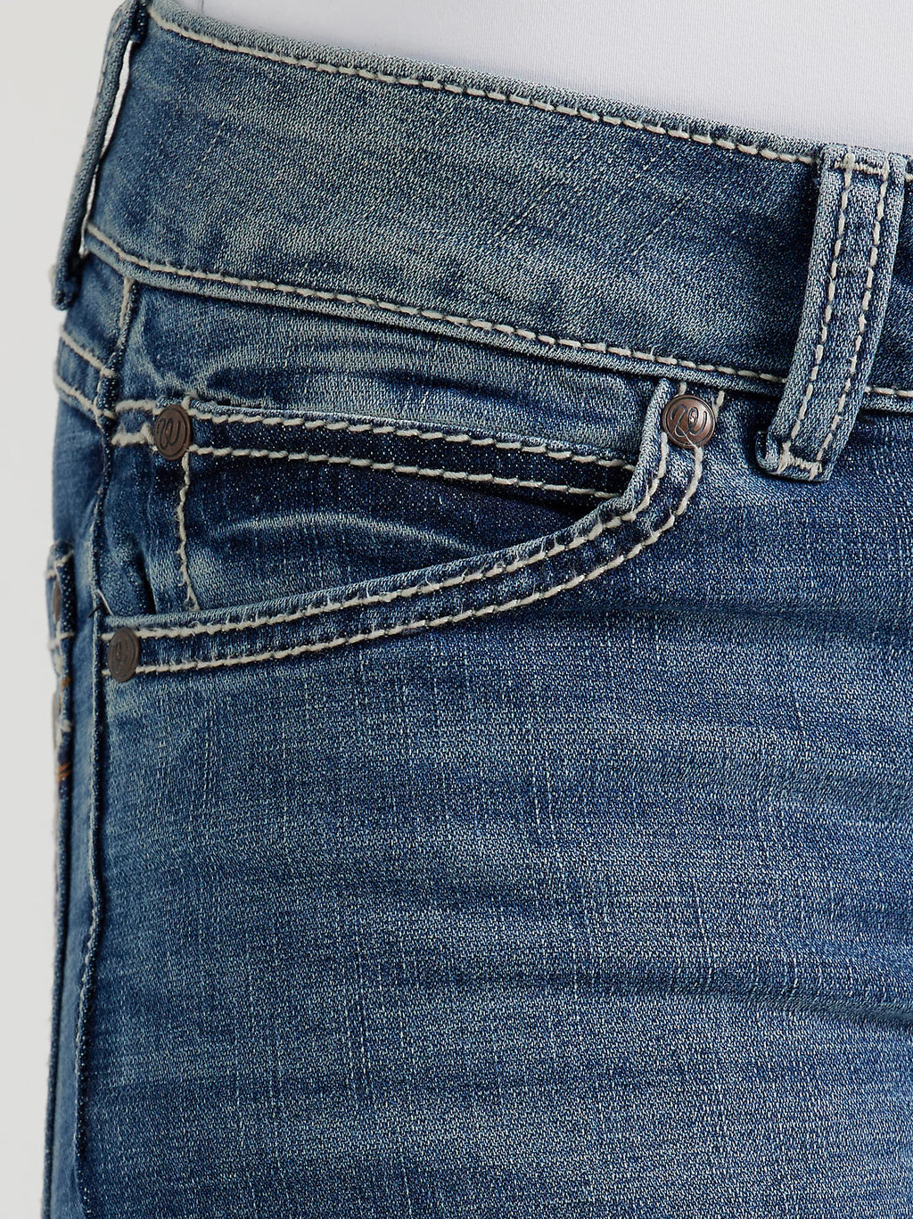 Close-up of blue jeans with stitching details on a light gray background