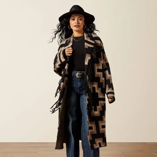 Woman wearing a long patterned coat and hat against a plain background