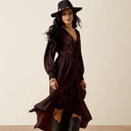 Woman wearing a dark brown dress and black hat against a beige background