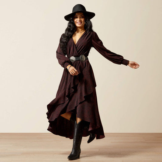 Woman wearing a long brown dress with a belt and black boots on a beige background
