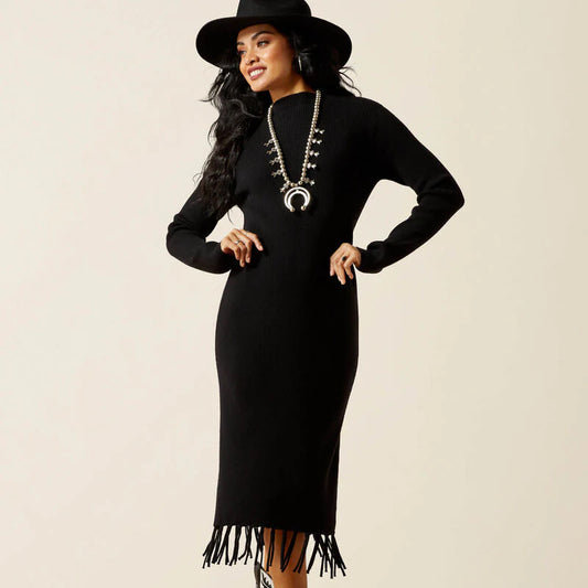 Woman wearing a black dress with fringe details and a matching hat on a beige background