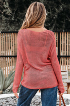 Person wearing a pink knit sweater and blue jeans standing outdoors.