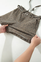 Leopard print top being held by hands on a white background