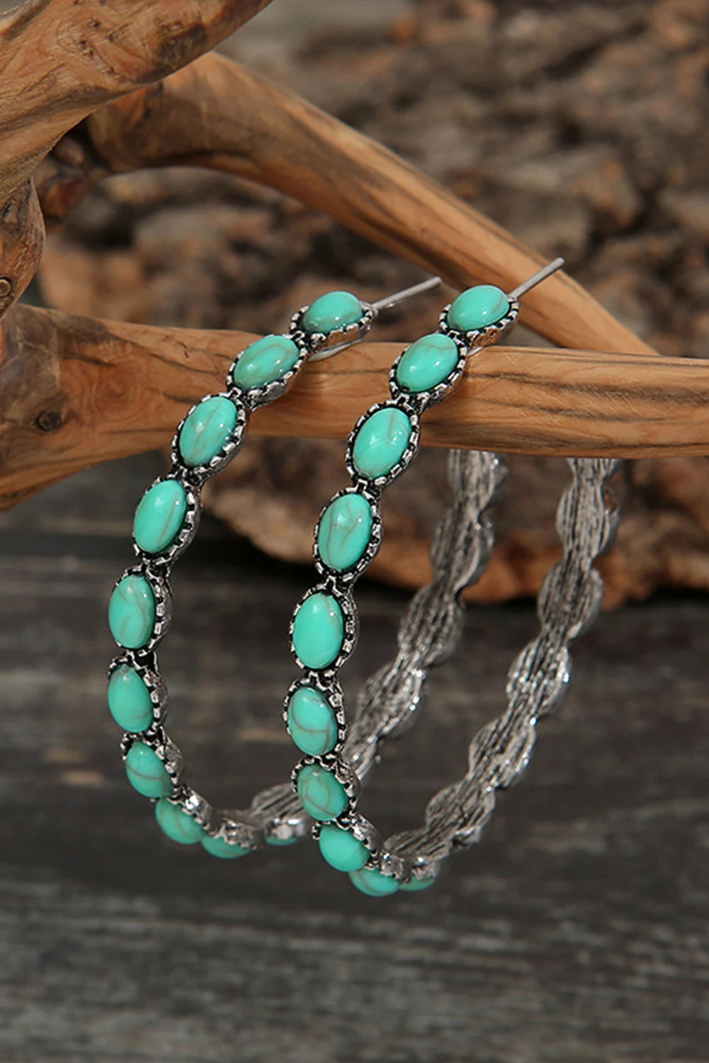 Turquoise hoop earrings on a wooden branch with a natural background