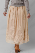 Beige lace skirt worn by a person on a gray background