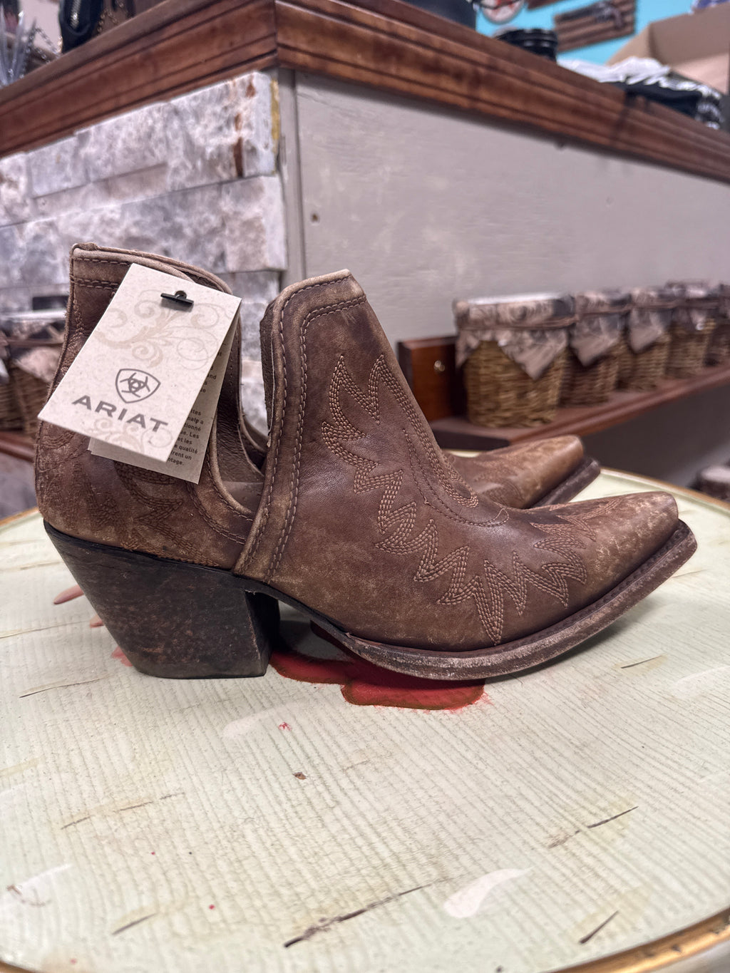 Brown cowboy boots with Ariat tag on a wooden surface