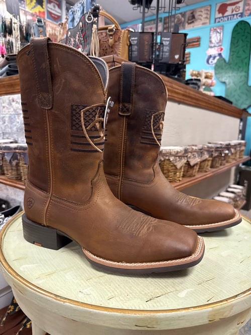 Brown leather boots with a decorative buckle on a wooden barrel in a store setting.