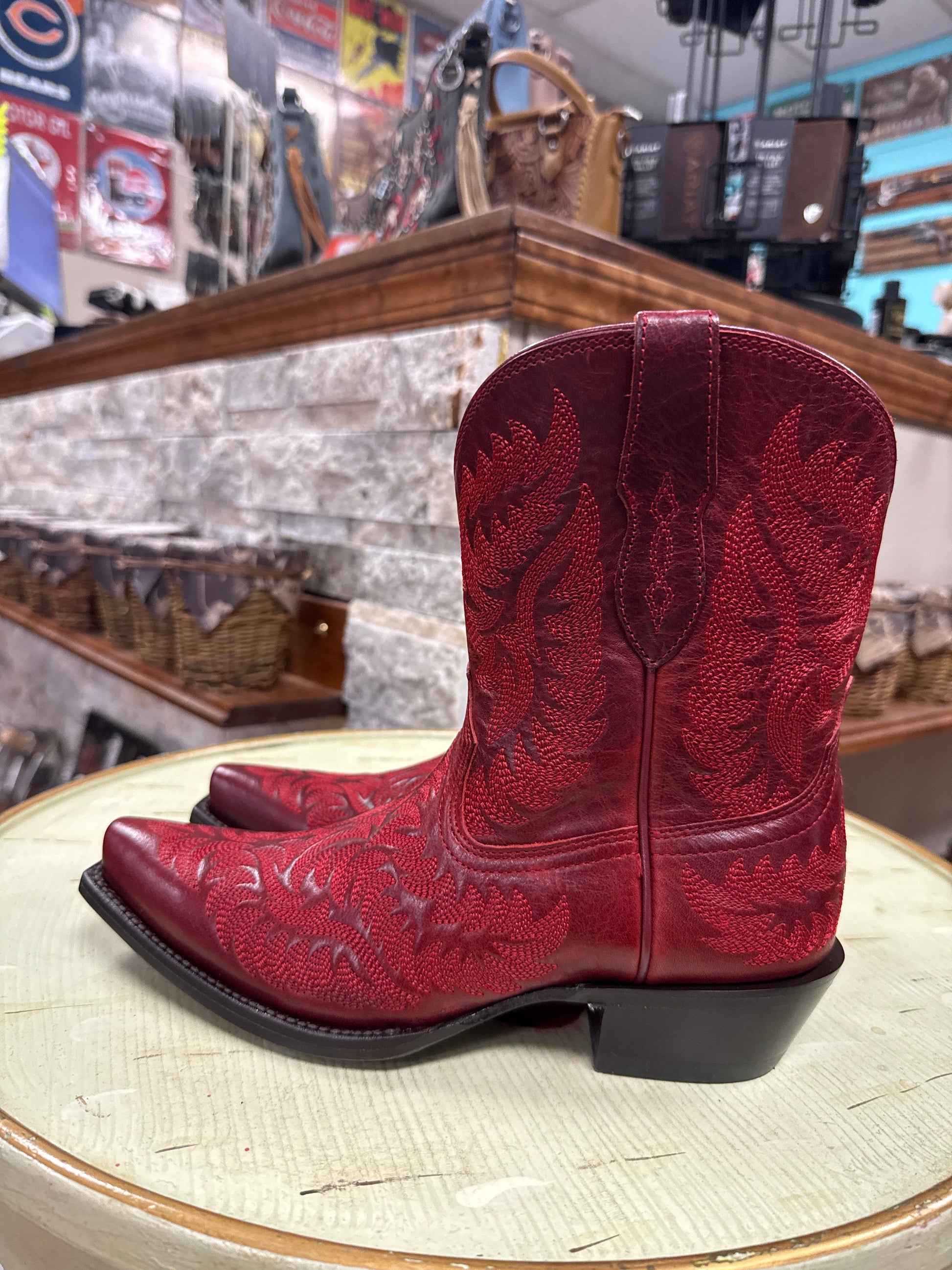 Red embroidered cowboy boot on a wooden block with a store interior in the background
