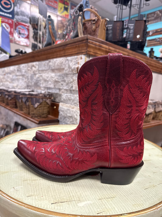 Red embroidered cowboy boot on a wooden block with a store interior in the background
