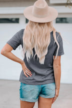 Person wearing a gray t-shirt and denim shorts with a beige hat, standing against a neutral background.