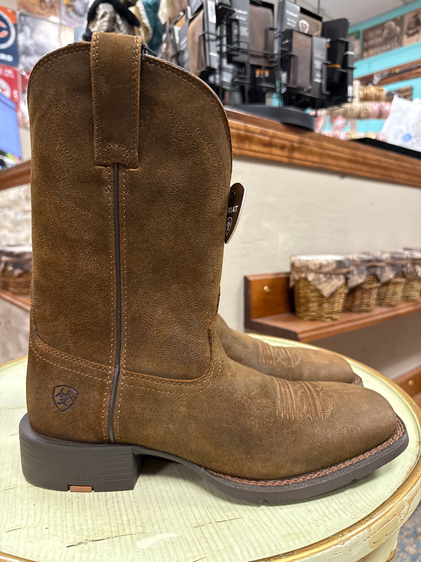 Brown boot with a visible brand logo on a blurred store background